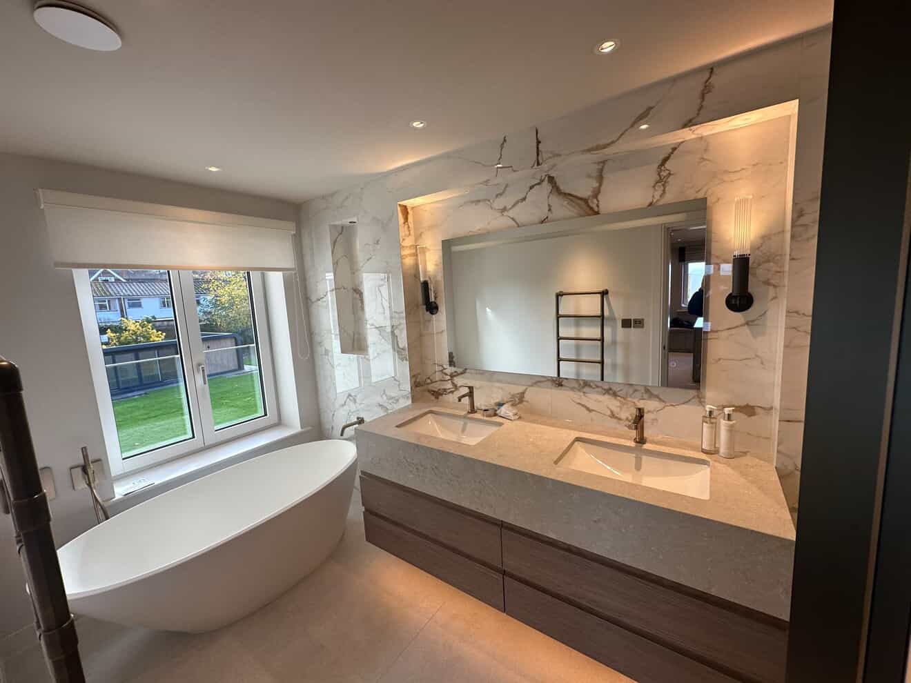 Luxury bathroom with freestanding bath, marble walls, backlit mirror and LED vanity lighting