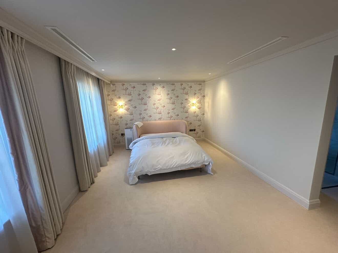 Elegant bedroom with recessed LED downlights and decorative wall sconces in luxury Surrey home