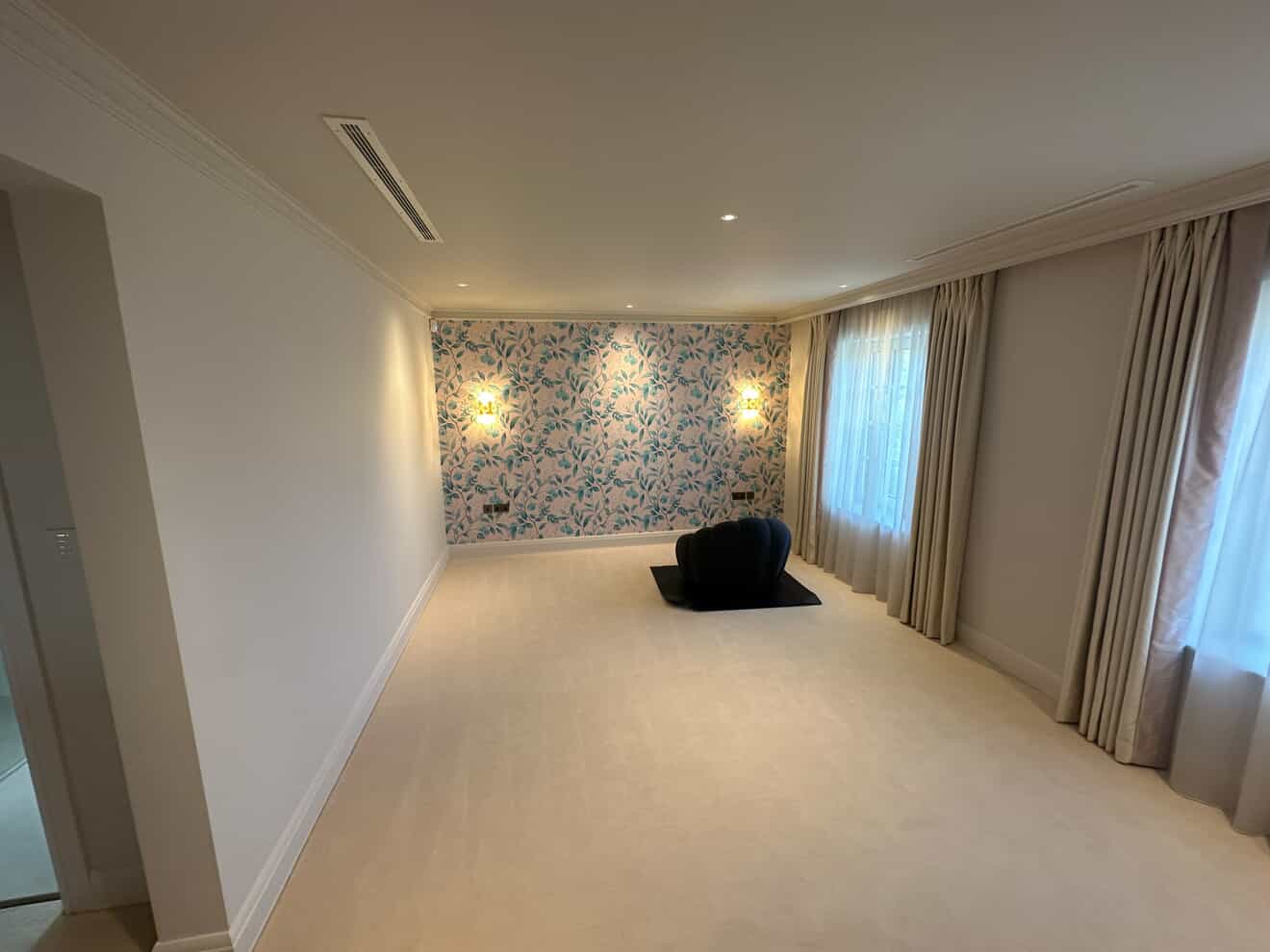 Bedroom with feature wallpaper, decorative wall sconces and recessed ceiling downlights