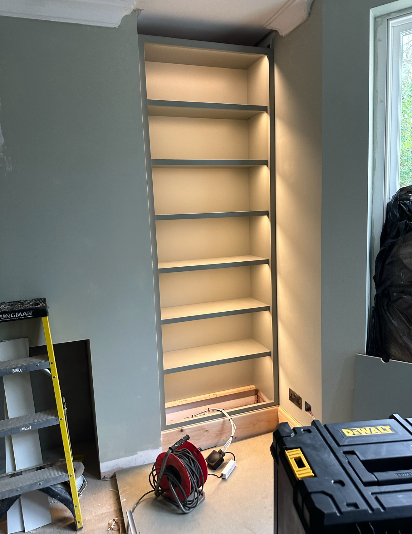 Custom bookshelf with warm white LED strip lighting installed by electrician in Surrey