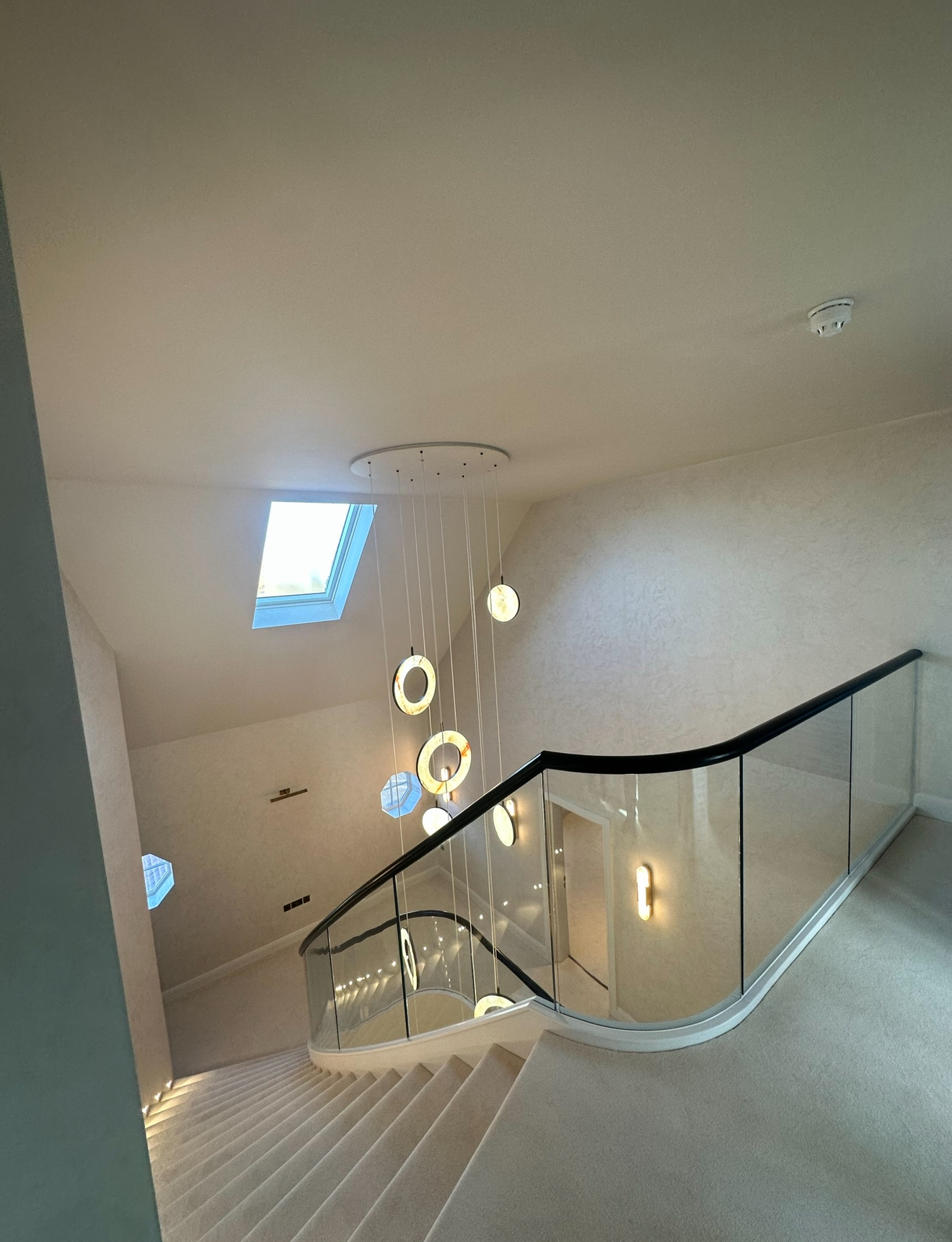 Pendant chandelier installation viewed from above with natural skylight in luxury property